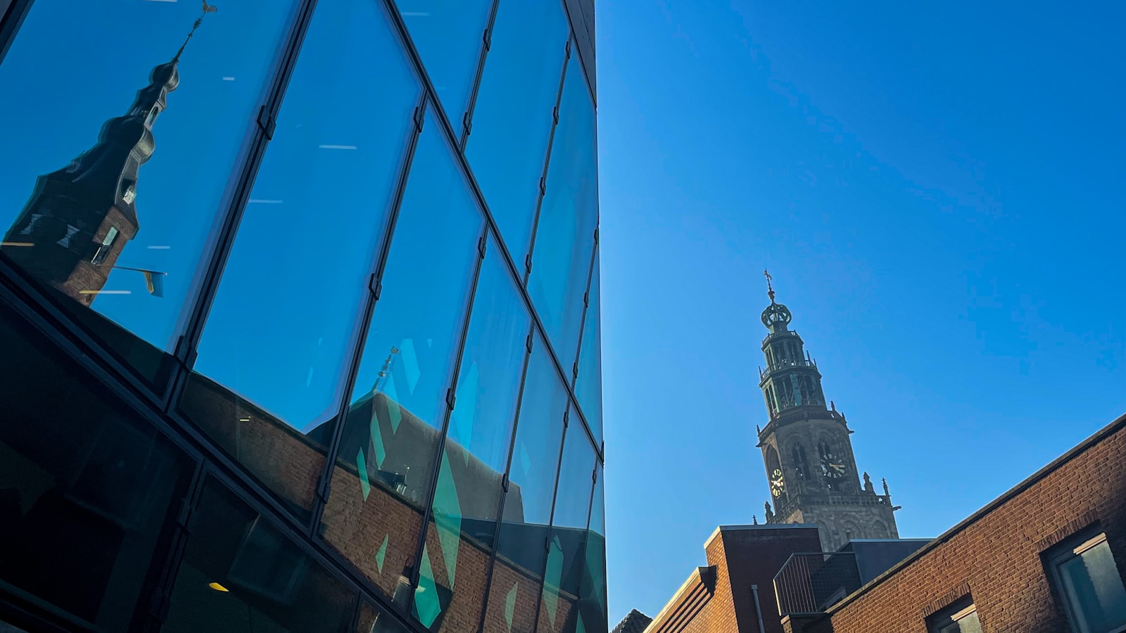 a tall building with a clock tower reflected in the windows
