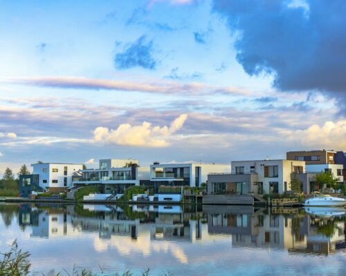 white and brown concrete buildings near body of water under blue and white cloudy sky during