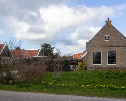 brown and white concrete house near green grass field under white clouds during daytime