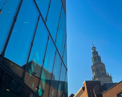 a tall building with a clock tower reflected in the windows